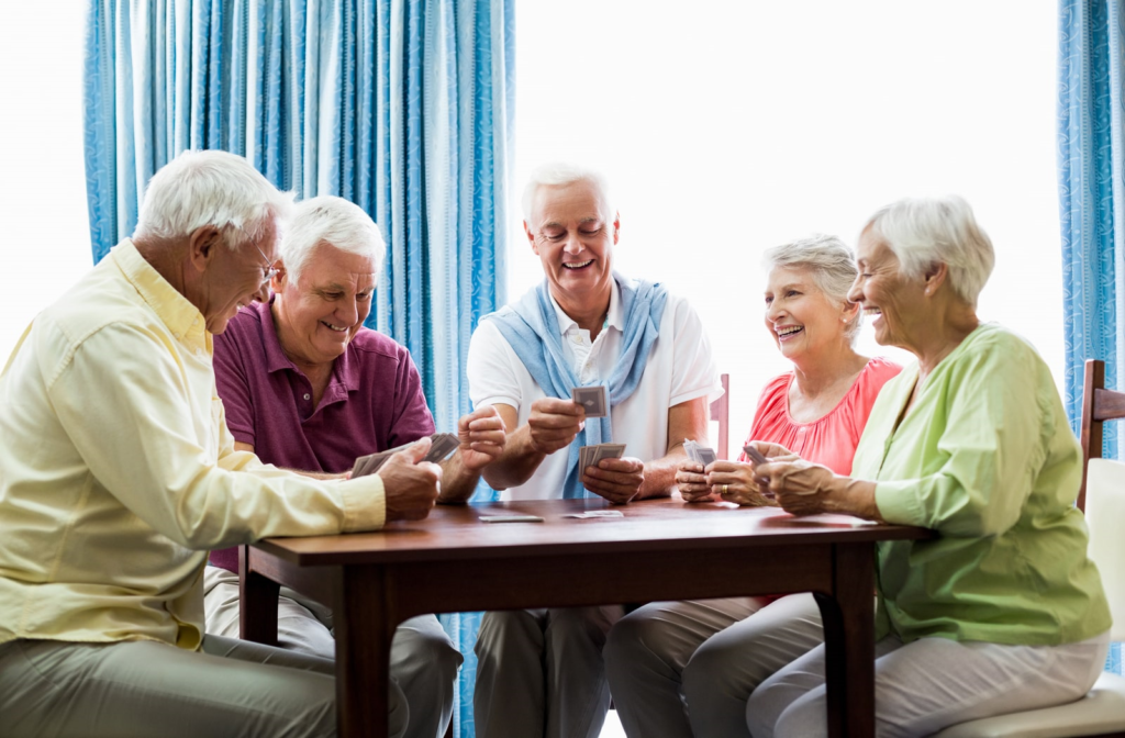 Independent living community members laughing and socializing over cards in a lounge area