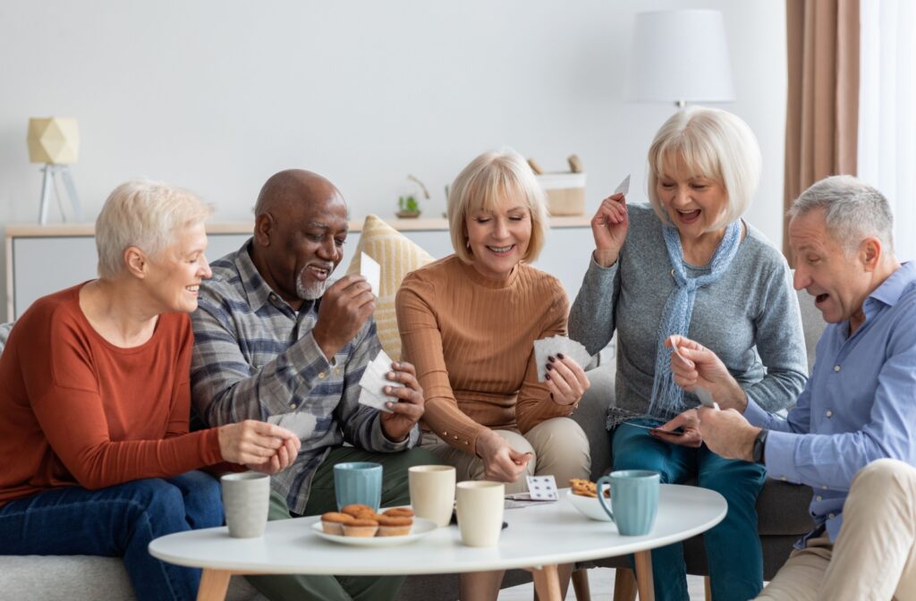 A group of seniors smiling together while playing a game of cards.