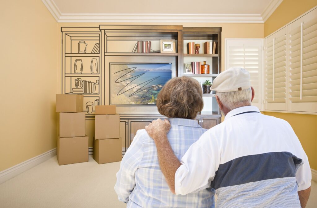 A senior couple stand shoulder to shoulder as they pack up their home to move into senior living.