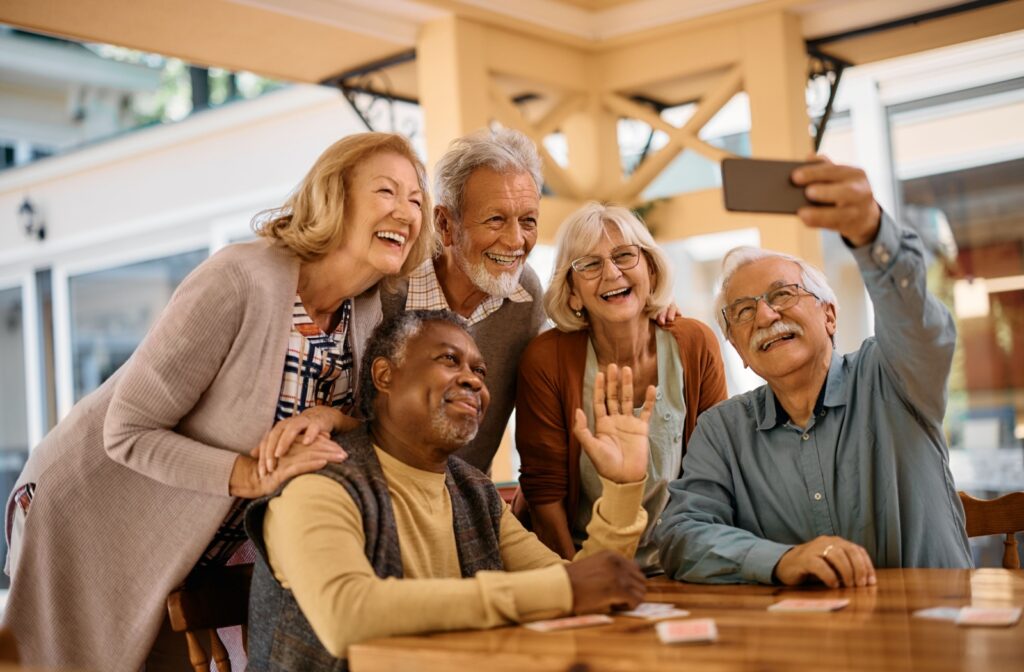 A group of happy seniors takes a group selfie in their retirement community.